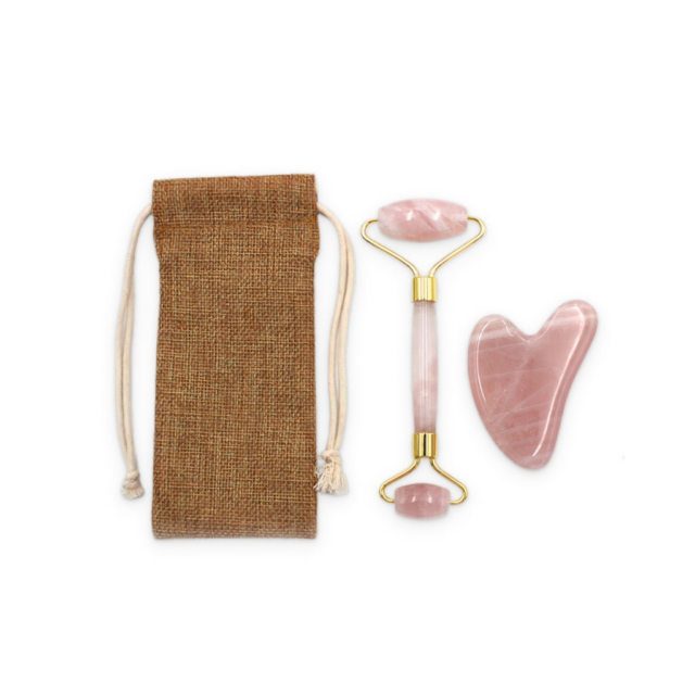 A gua sha and facial roller next to a tieable bag