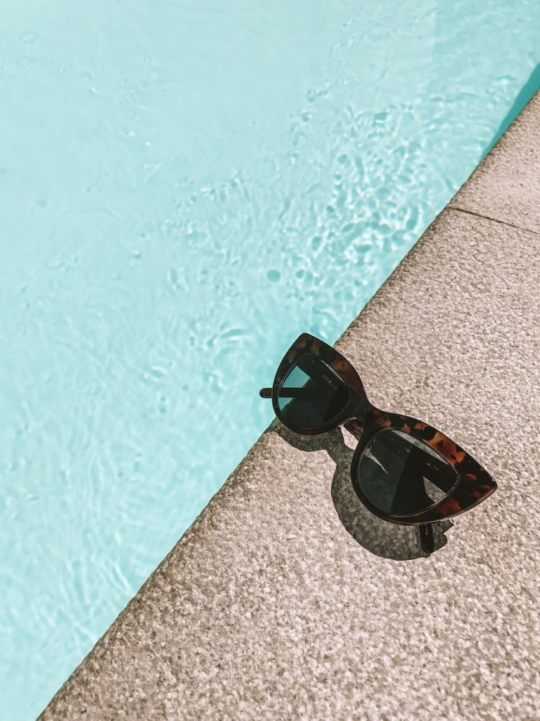 A pair of sunglasses next to a pool